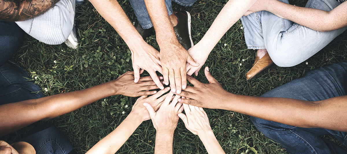 People stacking hands together in the park
